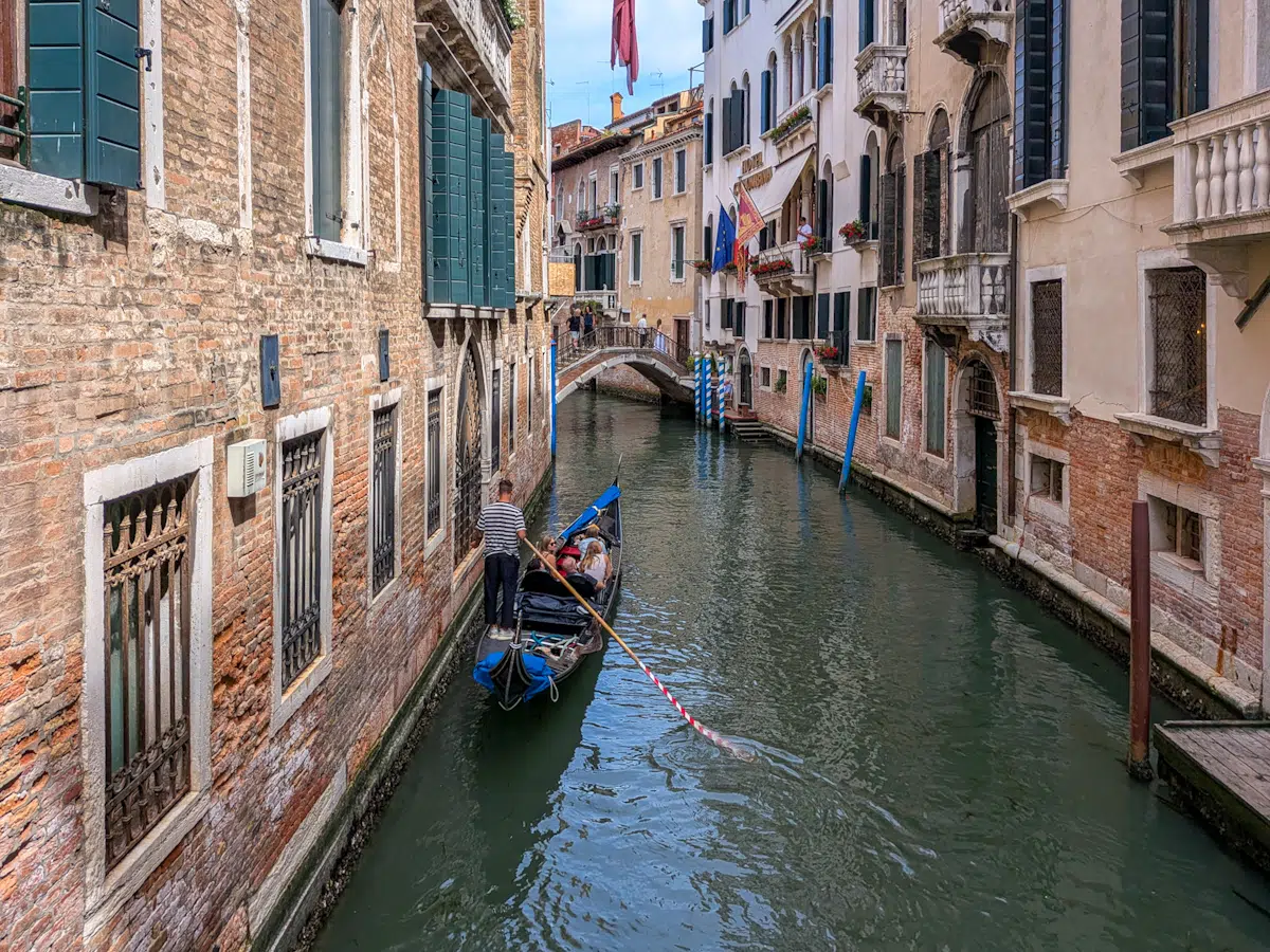 Schmaler Kanal in Venedig mit Gondel und bunten Palazzi im Sonnenlicht