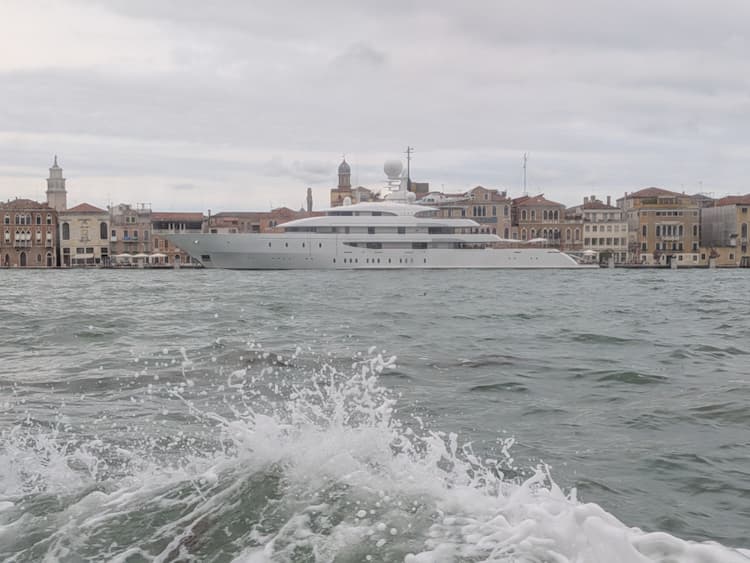 Blick vom schaukelnden Boot über die Lagune auf die Skyline von Venedig, Gischt im Vordergrund