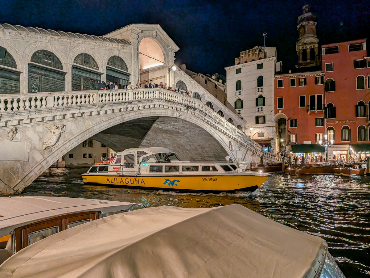 Rialtobrücke bei Nacht mit Wasserbus auf dem Canal Grande in Venedig